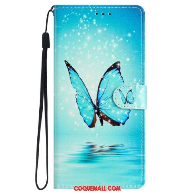 Housse iPhone 15 Papillon Bleu en Vol à Lanière